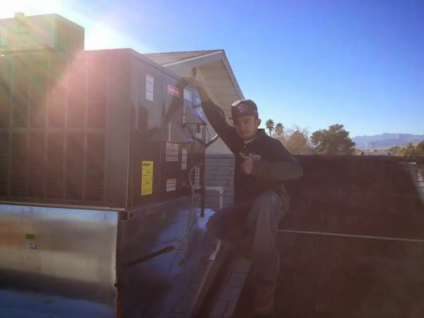 HVAC technician performing Heat Pump Repair on a rooftop unit in Clarkson